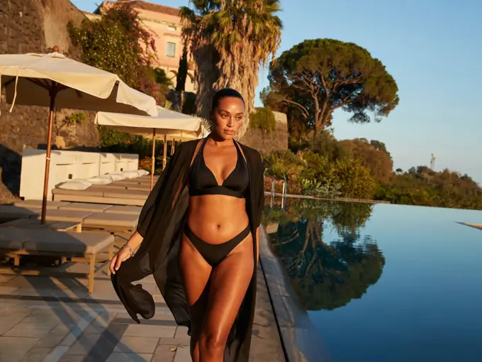 Dame i sort bikini og kimono ved basseng.