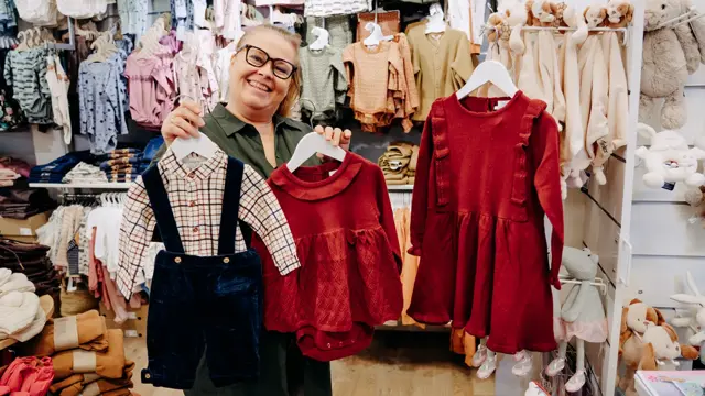 ansatt viser frem julekjoler og juledress