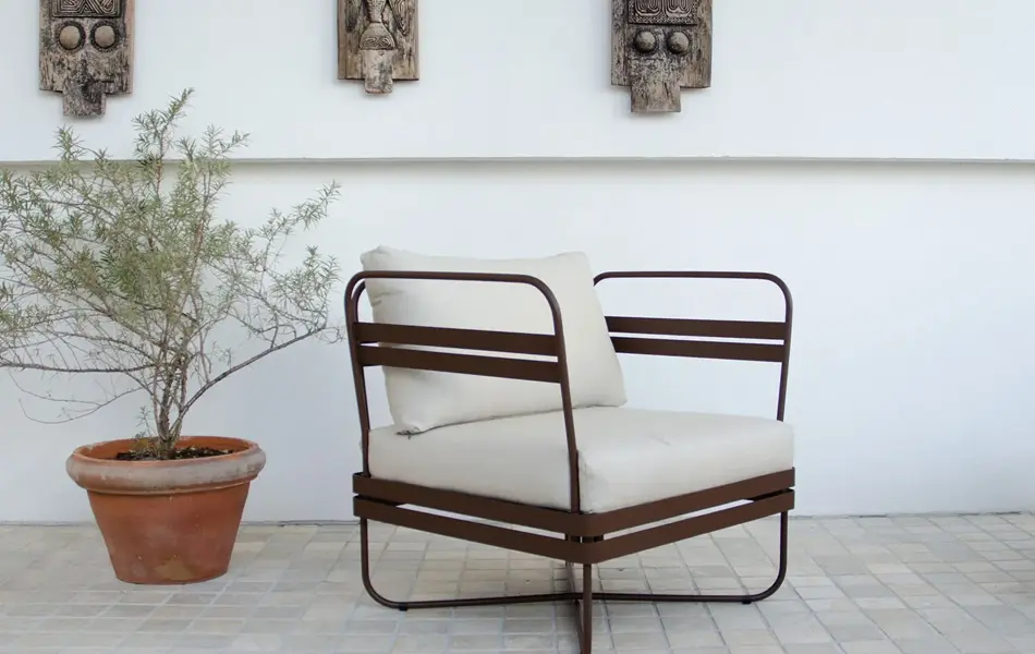 Brun stol med hvite puter og en grønn plante i terrakotta potte