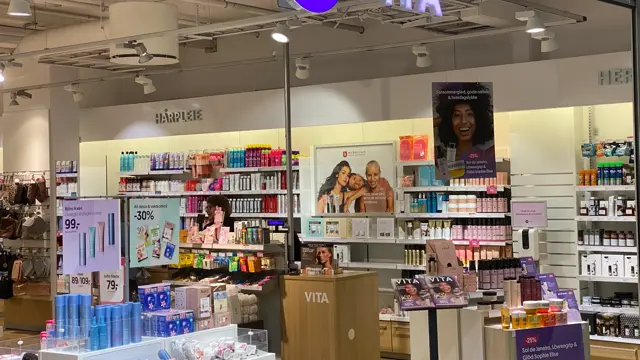 innendørs butikk med kosmetikk og reoler og lilla skilt