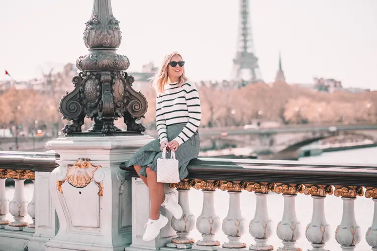 Dame med solbriller sitter på en bro