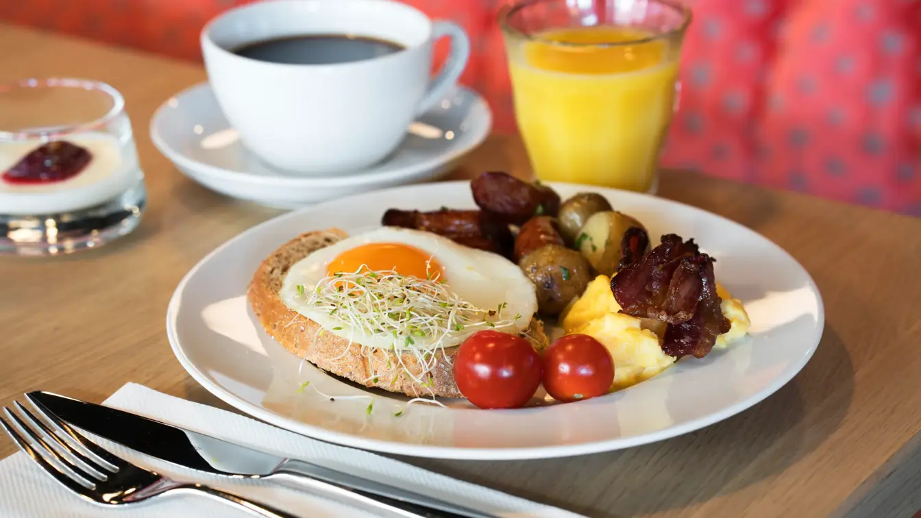 Frokosttallerken med egg og bacon og appelsinjuice som serveres i frokostsalen på Thon Hotel Orion i Bergen Sentrum
