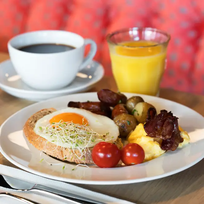 Frokosttallerken med egg og bacon og appelsinjuice som serveres i frokostsalen på Thon Hotel Orion i Bergen Sentrum