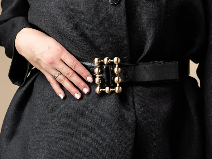 Vårens trender. Jente med halvlangt blondt hår inne i en butikk. Har på seg en trenchcoat, knall rosa kjole og en sort dressjakke med belter