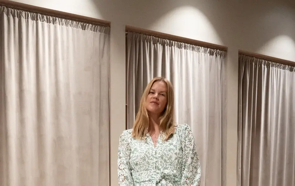 Dame med grønnblomstrete kort kjole, blå liten veske og hvite pumps med sløyfe.