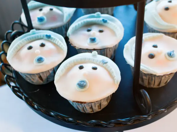 Close up of cupcakes on a cake stand for a baby shower. They are trimmed with pale blue