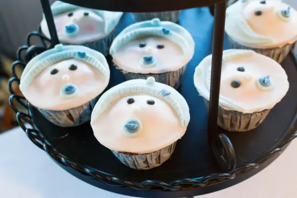 Close up of cupcakes on a cake stand for a baby shower. They are trimmed with pale blue
