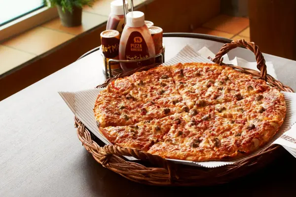 Pizza i kurv med dressinger på siden