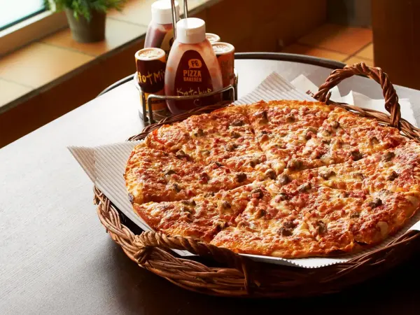 Pizza i kurv med dressinger på siden