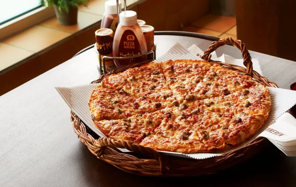 Pizza i kurv med dressinger på siden