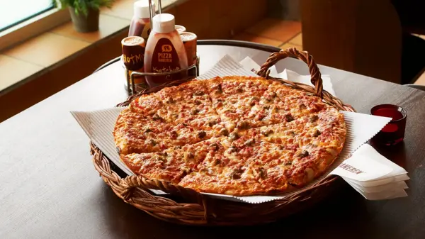 Pizza i kurv med dressinger på siden