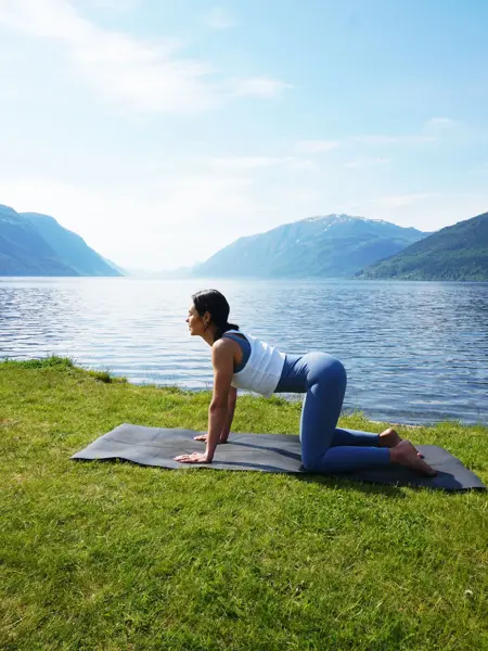 anny johansen viser yogaøvelser foran vakker fjord