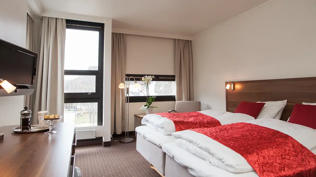 TV, skrivebord og dobbeltseng i rom på Thon Hotel Otta