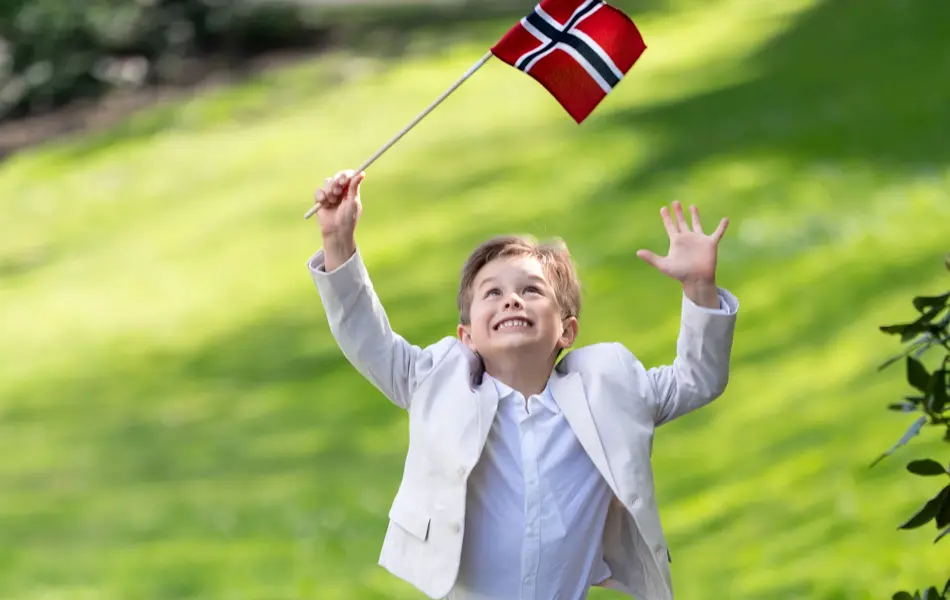 Liten gutt i hvit dress, hvit skjorte og blå sneakers.