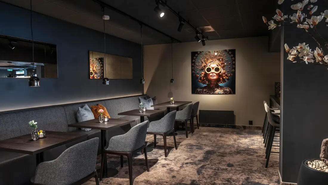 Frokostsal med dempet belysning, teppegulv, mørke møbler.