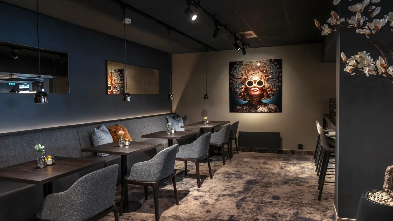 Frokostsal med dempet belysning, teppegulv, mørke møbler.