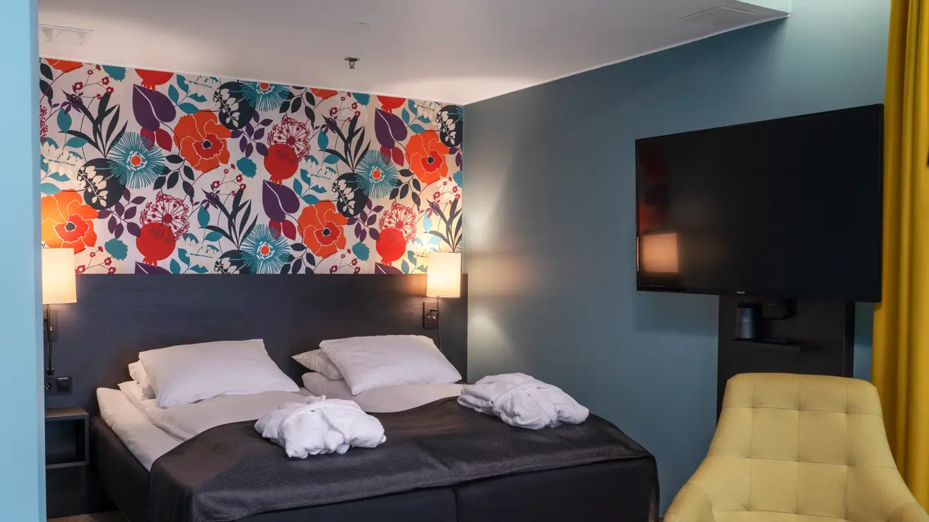 Blomstrende veggtapet med blå vegger, gule gardiner, gul stol og dobbeltseng