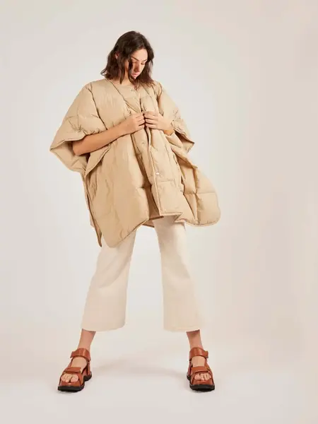 Dame i hvite-/sandfargede klær og chunky skinnsandaler. Illustrasjonsbilde til artikkel om vårmote for sko.