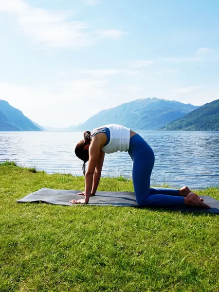 anny johansen viser yogaøvelser foran vakker fjord