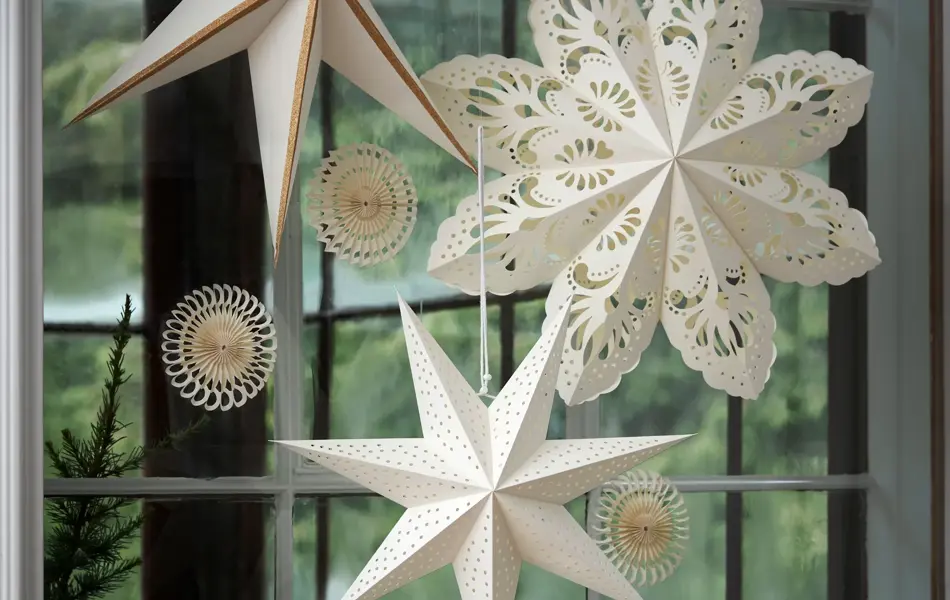 ulike varianter av hvite julestjerner opphengt i et vindu