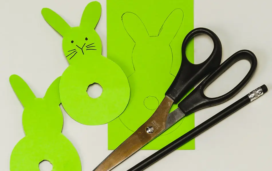 To grønne kaniner, et grønt ark, en blyant og en saks