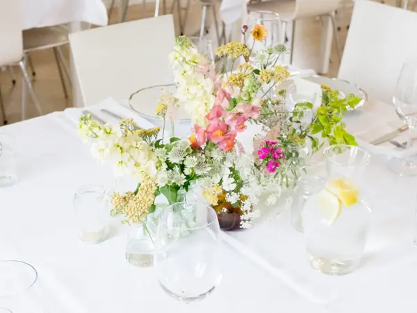 Hvitdekket bord dekorert med markblomster i små vaser