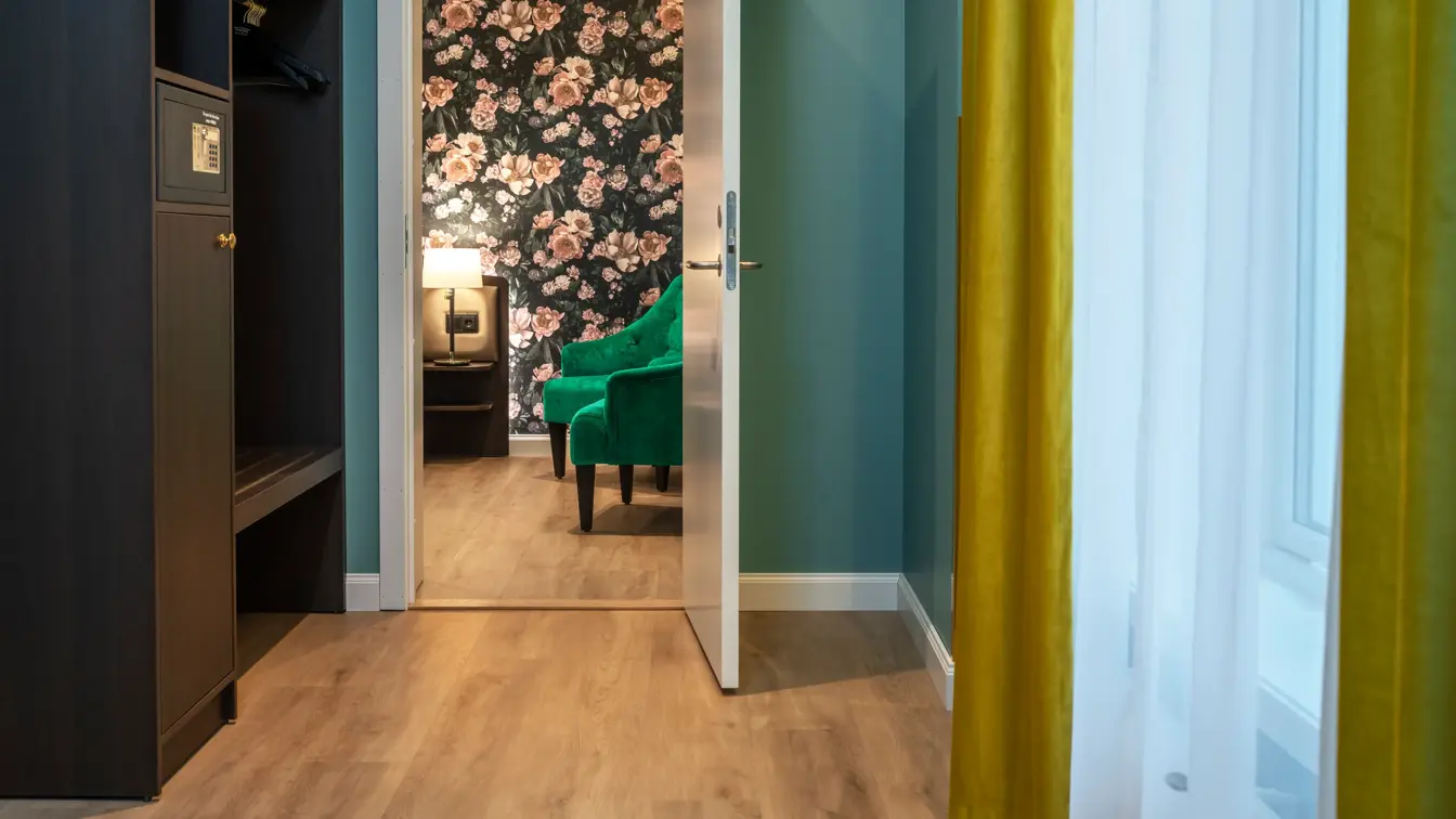 Gang med mørkt klesskap med safe, vindu med gule gardiner og dør inn til soverom.  business rom på Thon Hotel Høyers i Skien.