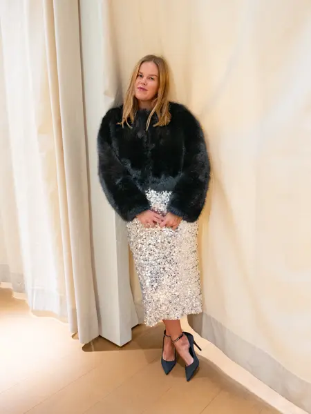 Dame med sort fuskepels, paljettskjørt og sorte pumps.