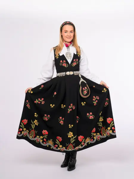 Jente som løfter på skjørtet i en svart bunad