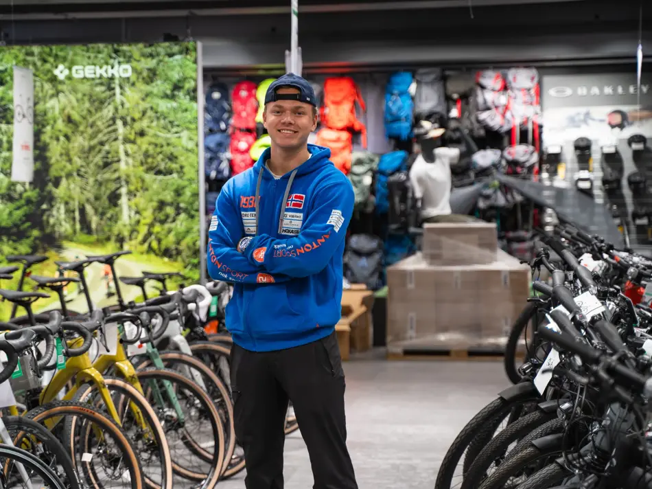 Mann som står blant sykler utstilt i butikken