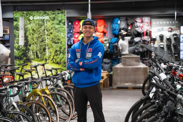 Mann som står blant sykler utstilt i butikken