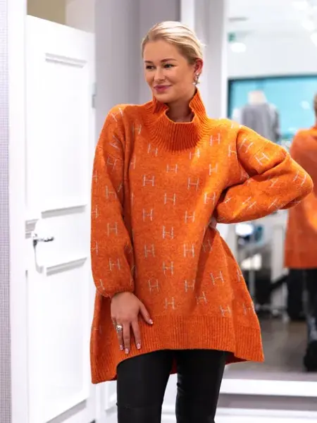 Jente med blondt hår, har på seg en orange genserkjole