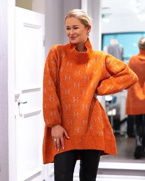 Jente med blondt hår, har på seg en orange genserkjole
