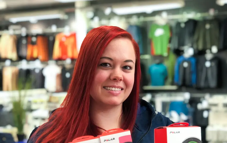 Smilende ansatt hos Intersport viser frem pulsklokker fra Polar