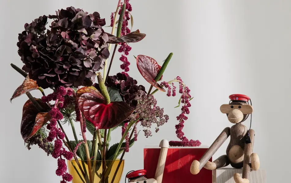 Bord med vase med blomster og Kaj Boyesen apekatter med rød russelue.
