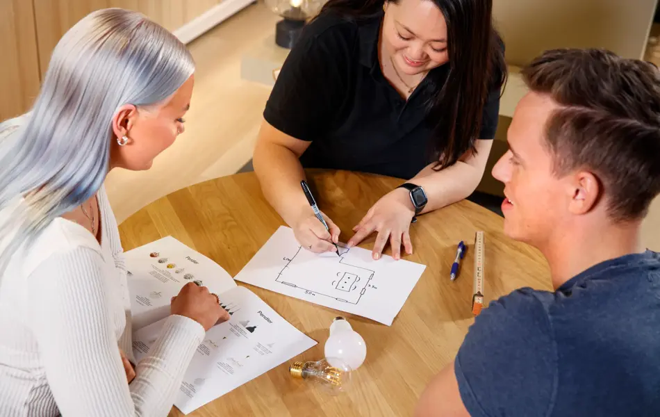 Lysplanlegging rundt bord med 3 mennesker, en lysplanlegger og et ungt par som er kunder