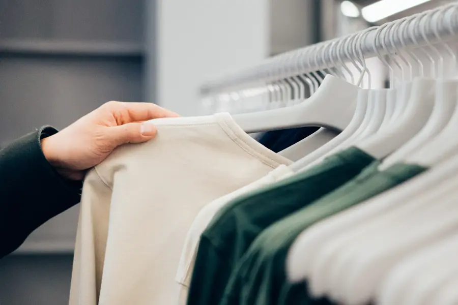 Klesstativ med beige og grønne klær i butikk