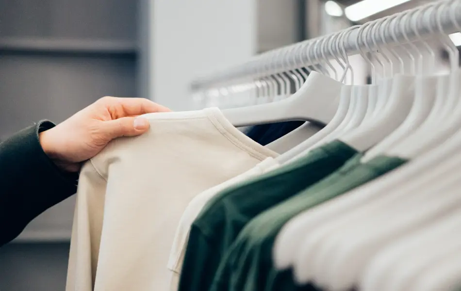 Klesstativ med beige og grønne klær i butikk