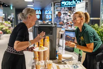 Senterleder Christina på AMFI Vågsbygd står bak en bod og deler ut kaffe og kake til senterkunder