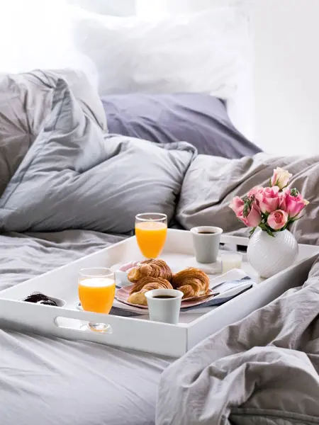 Et brett med mat og drikke på i sengen