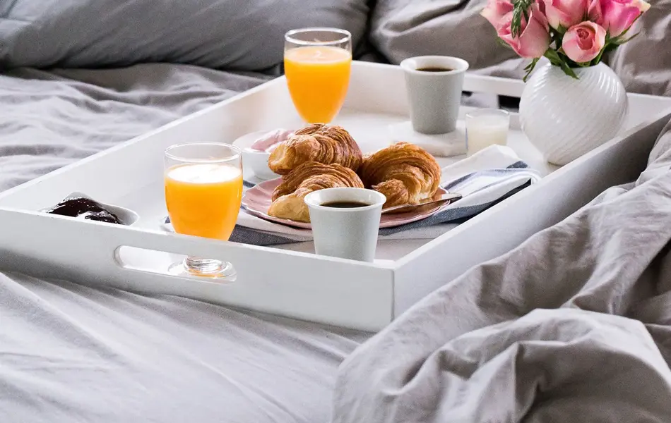 Et brett med mat og drikke på i sengen