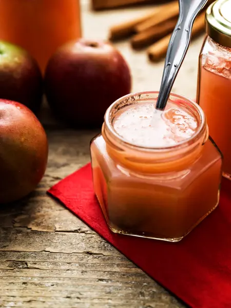 Deutschland, Baden-Württemberg, still life von frischem Apfelmus aus Bioäpfeln. Gefüllte Einmachgläser auf einem Holztisch