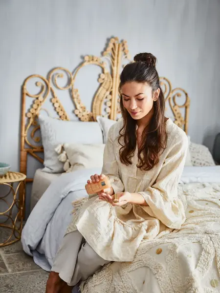 kvinne som sitter på seng med rituals-produkt