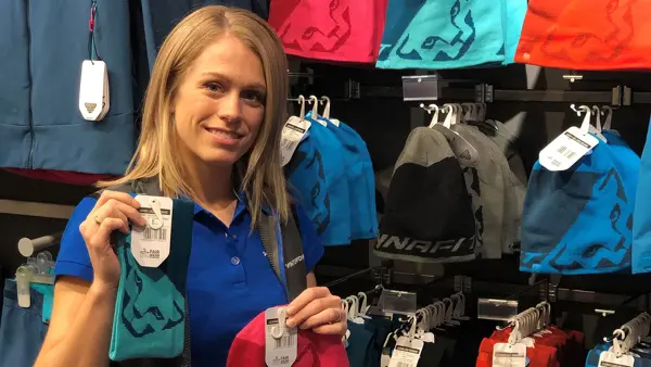 ansatt hos intersport viser frem fargerike luer og pannebånd