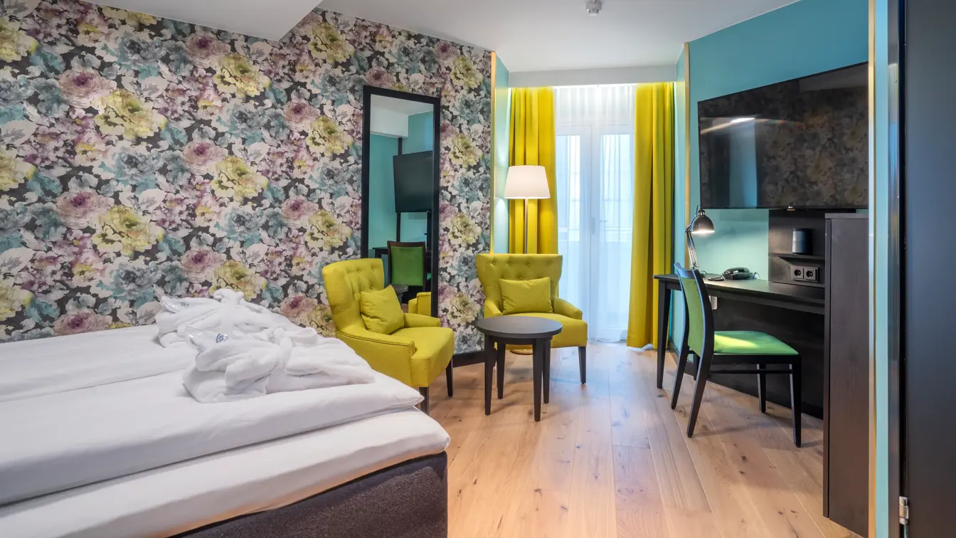 Blomstret tapet og stor dobbeltseng, speil, tv, i superiorrom på Thon Hotel Cecil i Oslo sentrum