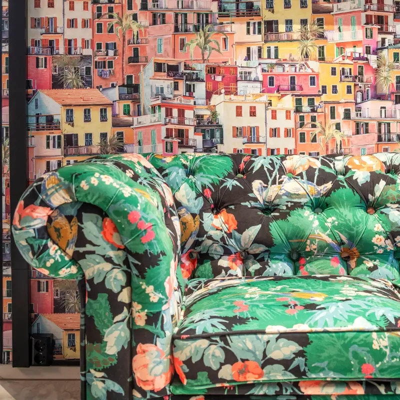 Tapetvegg med bilder av hus, sofa i ulike farger, speil på veggen 