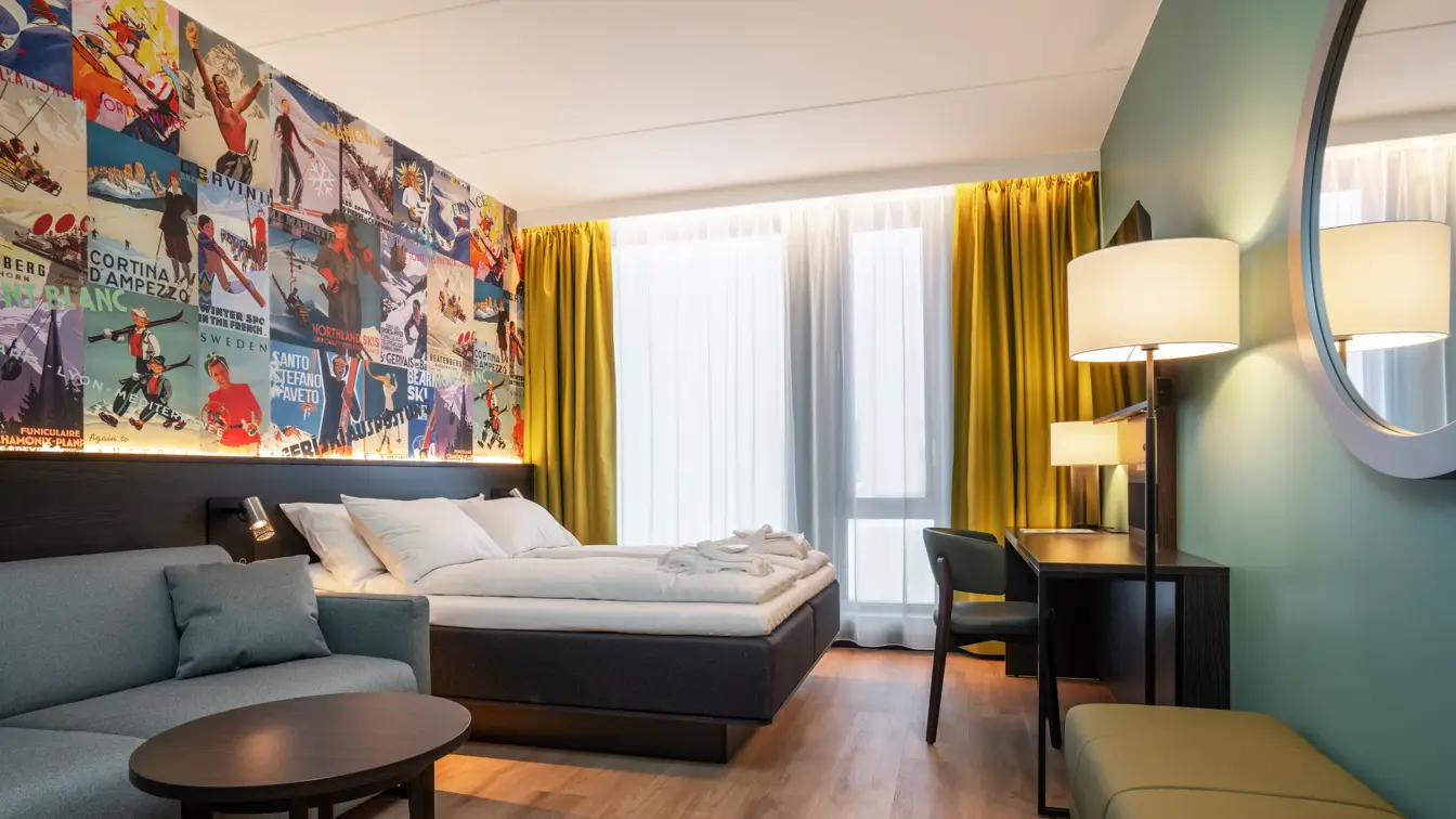 Sofa, skrivebord og dobbeltseng med rundt speil på veggen