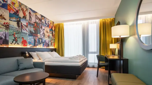 Sofa, skrivebord og dobbeltseng med rundt speil på veggen