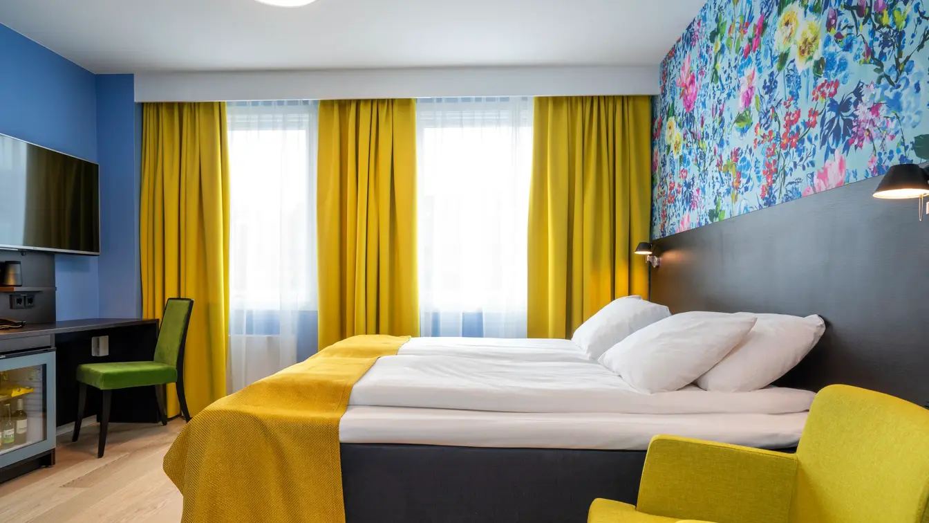 Stol, dobbeltseng, skrivebord og blomstrete tapet på Thon Hotel Moldefjord
