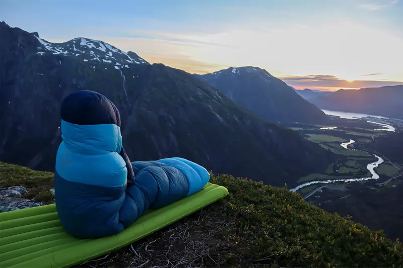 Noen som sitter i en sovepose og ser på utsikten